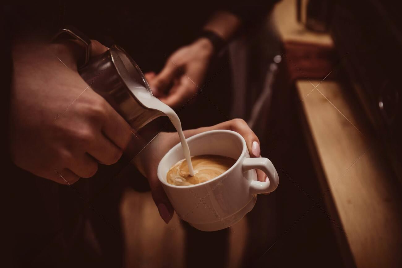 131219257-barista-makes-flavored-cappuccino-pours-milk-into-coffee-transformed